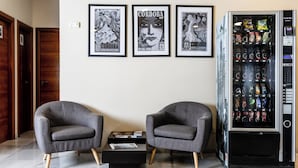 A modern room with two grey armchairs, a black coffee table, and a vending machine stocked with beverages.