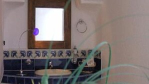 A bathroom with a tiled backsplash, a sink, and a window above the mirror. - Hotel El Refugio (Tlaxcala)