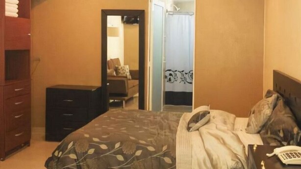 A bedroom with a bed, a dresser, a mirror, and a bathroom visible through an open door. - Hotel El Refugio (Tlaxcala)