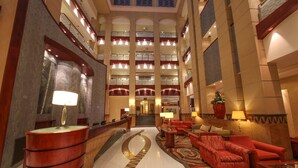A spacious lobby with a curved reception desk, multiple seating areas, and a central staircase leading to upper floors. - Kigali Serena Hotel (Kigali)
