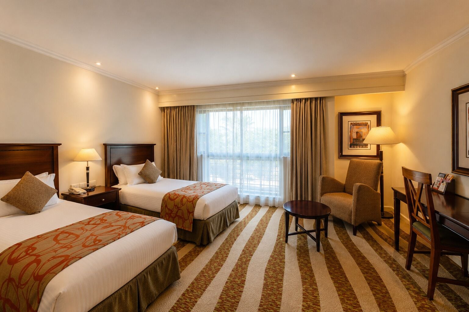 A hotel room with two beds, a desk, a chair, a small table, and a window with curtains.