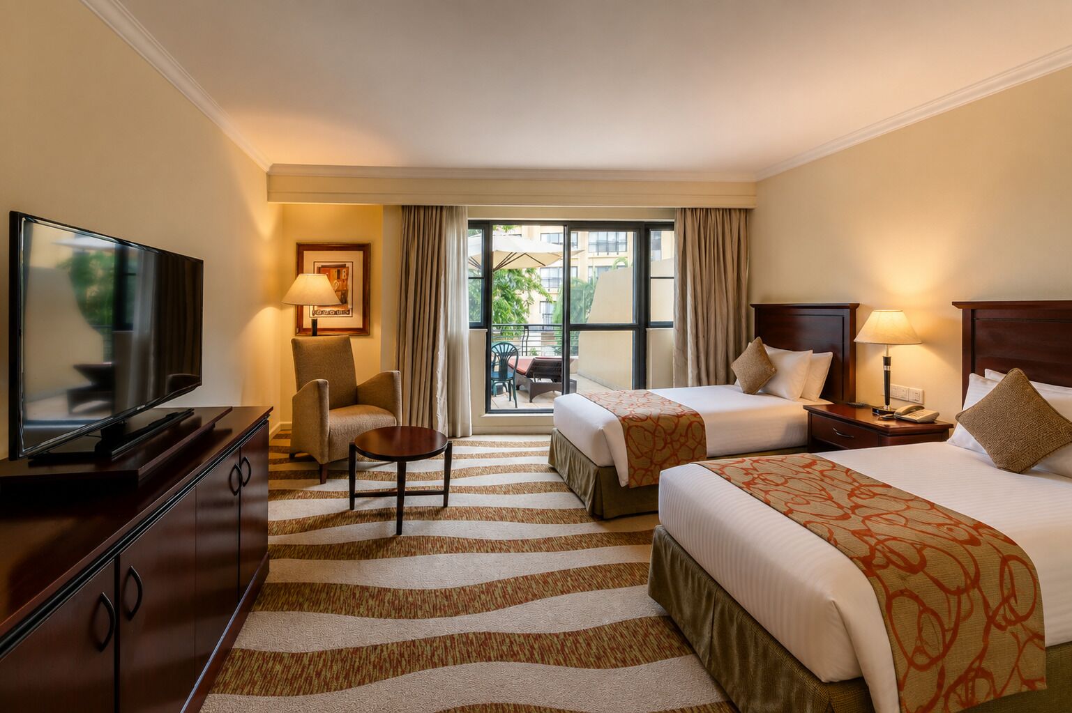 Une chambre d’hôtel avec deux lits, une télévision, un bureau et une vue sur l’extérieur.
