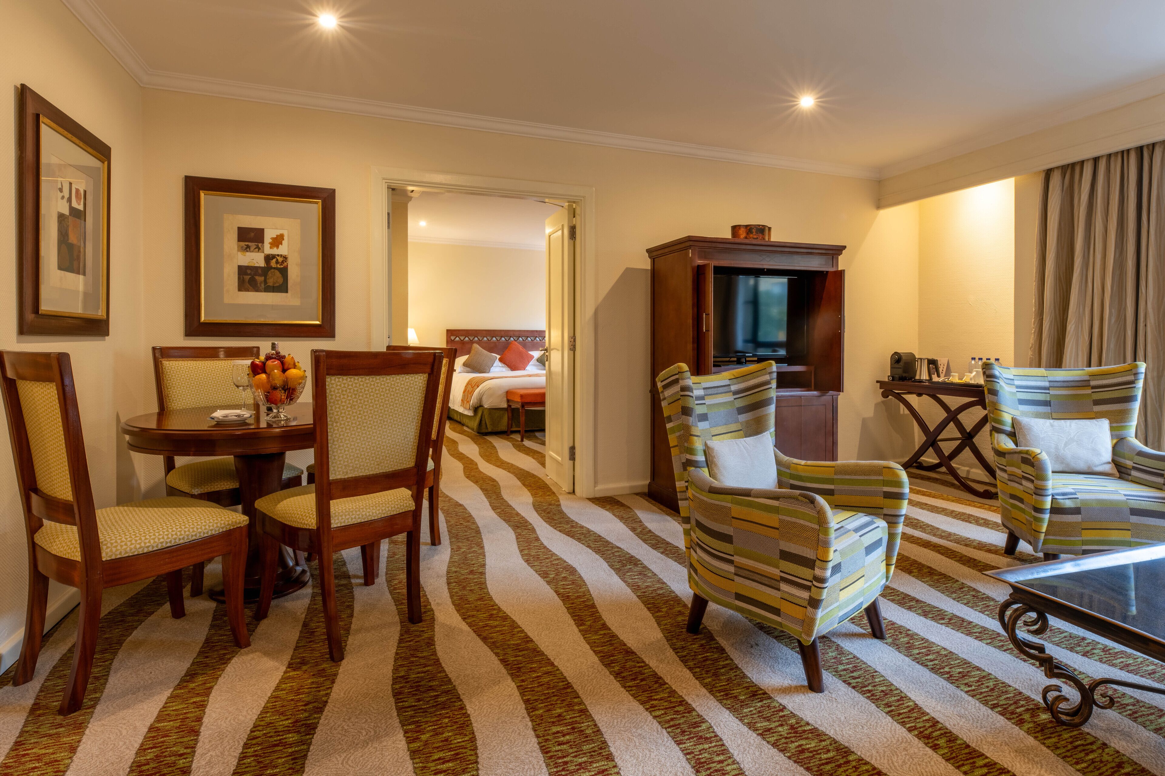 Habitación de hotel con comedor, televisión y cama.