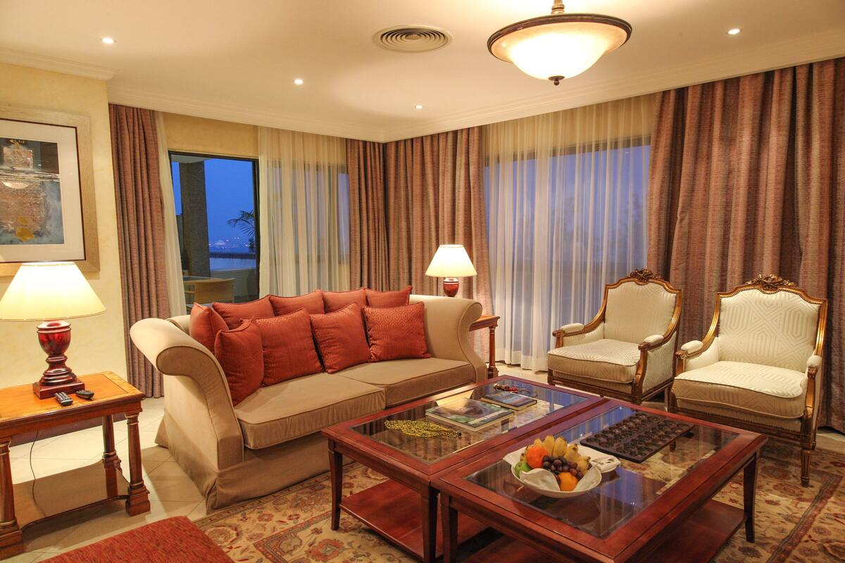 A living room with a sofa, two armchairs, a coffee table, and a lamp.