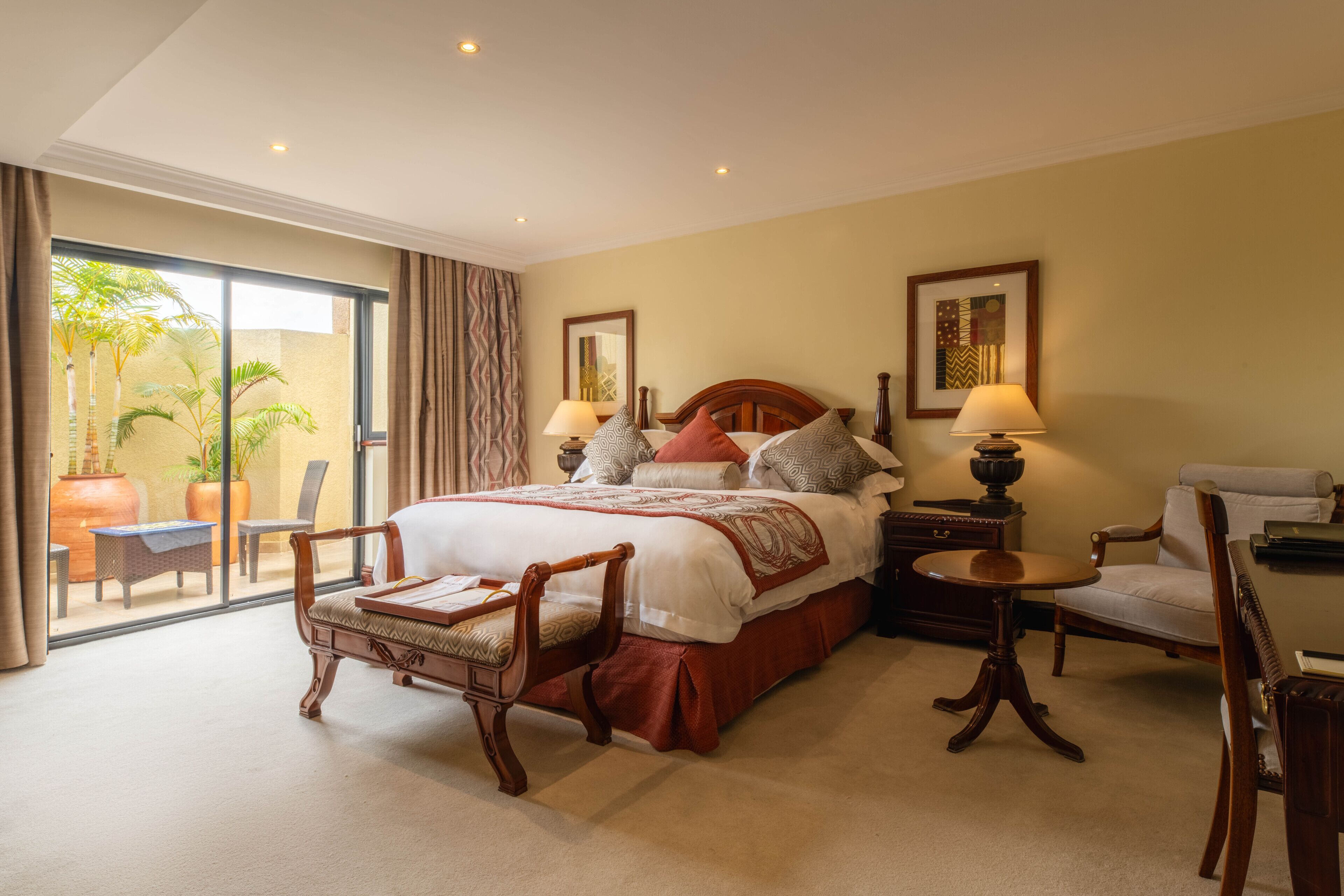 A hotel room with a large bed, two bedside tables, a chair, a desk, and a view of the outdoors.