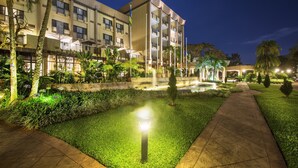 A well-lit hotel courtyard with a central water feature, surrounded by palm trees and a paved walkway. - Kigali Serena Hotel (Kigali)