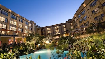Un patio de hotel con piscina rodeado de exuberante vegetación y palmeras.