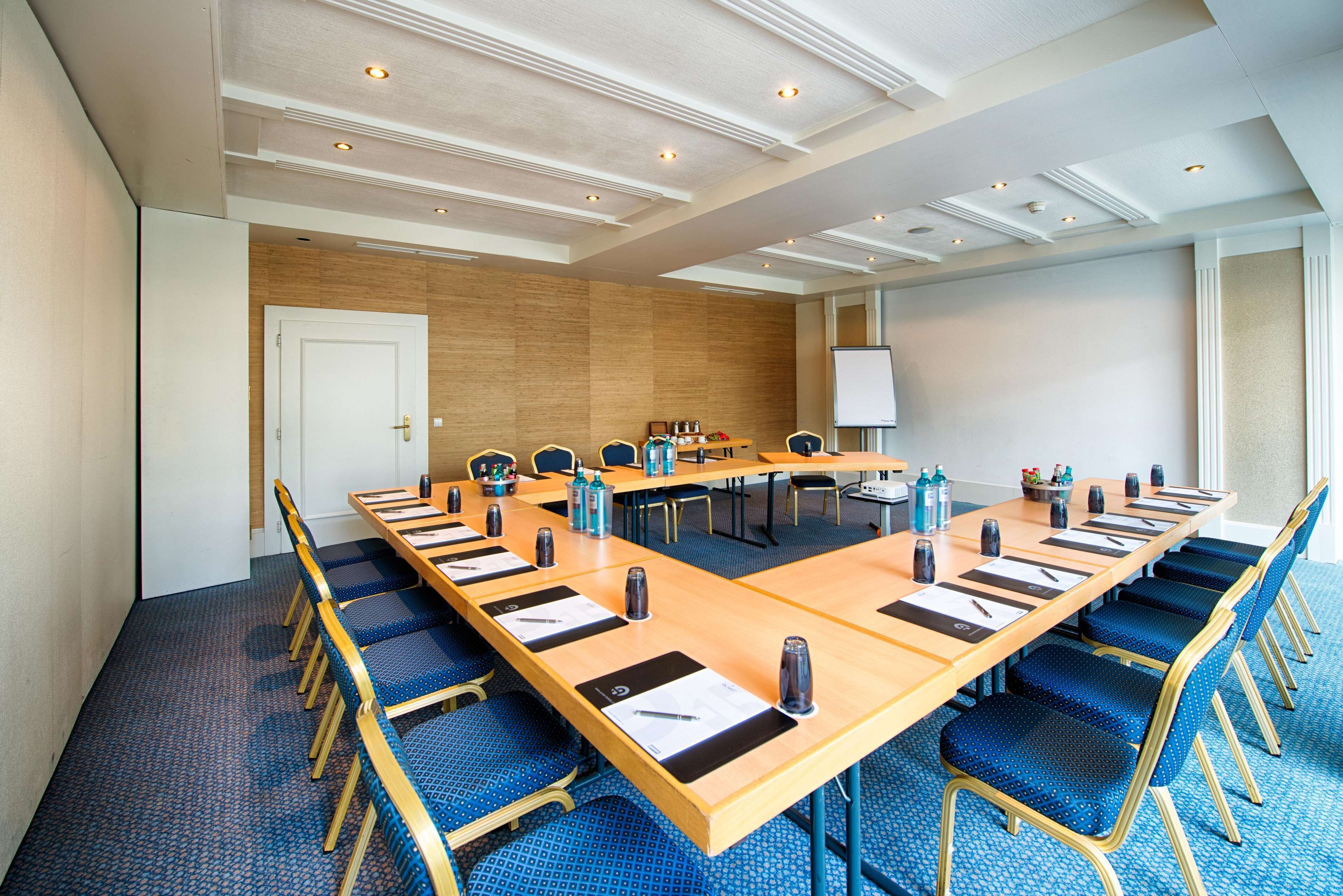 Une salle de conférence avec une longue table, des chaises bleues et un tableau blanc.