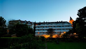 Un hôtel à plusieurs étages, doté d’une tour imposante et d’une entrée bien éclairée.