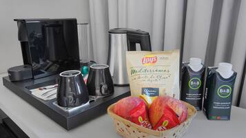 Un plateau de petit-déjeuner comprenant une machine à café, une théière et un panier de fruits.