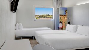 A hotel room with two single beds, a desk, and a chair. There is a window with a view of a green landscape and buildings. - B&B Hotel Barcelona Granollers (Les Franqueses del Valles)