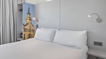 Una habitación de hotel con una cama grande, ropa de cama blanca, un aplique de pared y un panel decorativo con una imagen de un edificio.