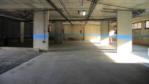 An indoor parking garage with concrete pillars, blue safety lines, and fire extinguishers. - B&B Hotel Barcelona Granollers (Les Franqueses del Valles)
