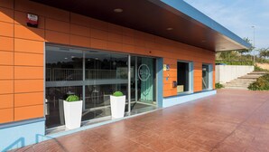A modern building with a glass entrance, outdoor seating, and a clear sky. - B&B Hotel Barcelona Granollers (Les Franqueses del Valles)