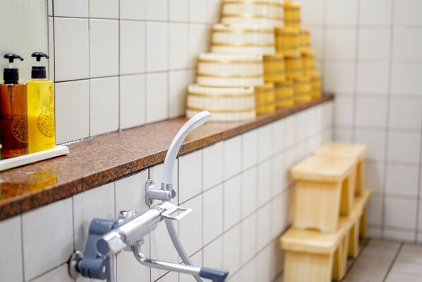 Ett badrum med en bänkskiva i marmor, en handtork och hygienartiklar som är staplade.