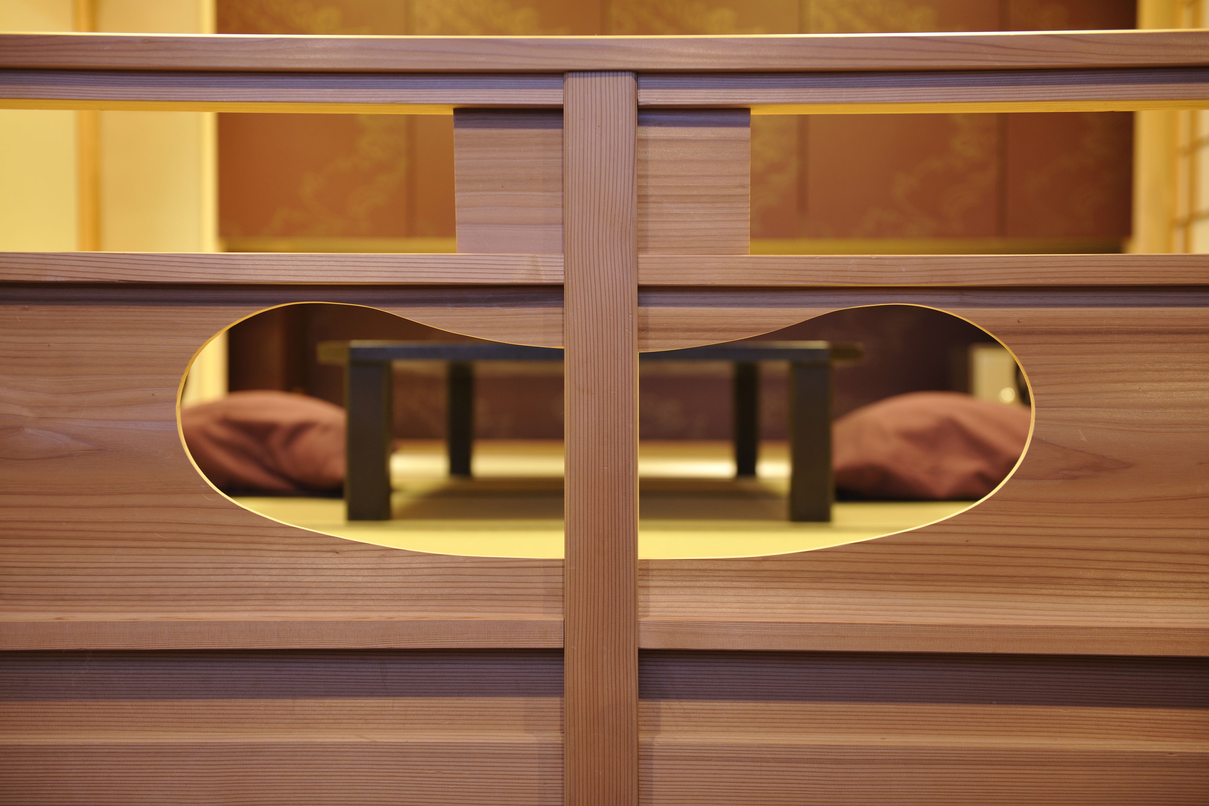 A wooden bed frame with a circular cutout in the center, revealing a bed with pillows.