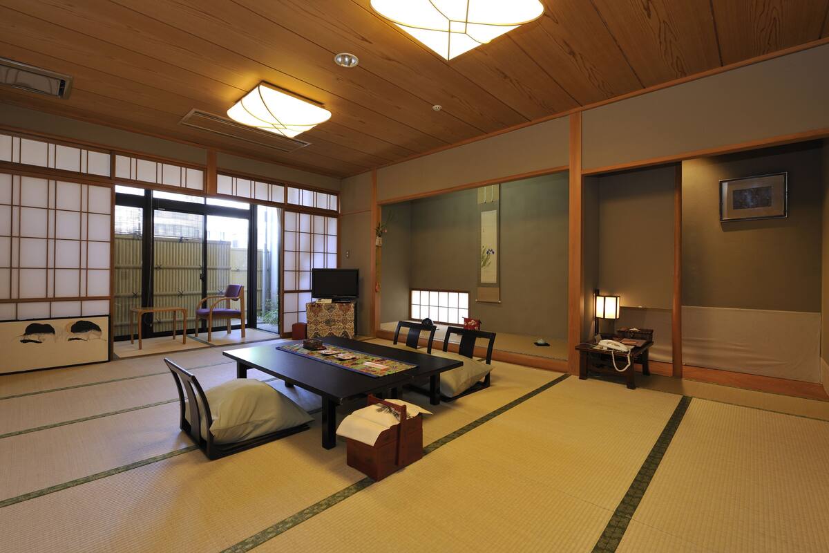 A traditional Japanese room with tatami flooring, a low table with cushions, and sliding doors.