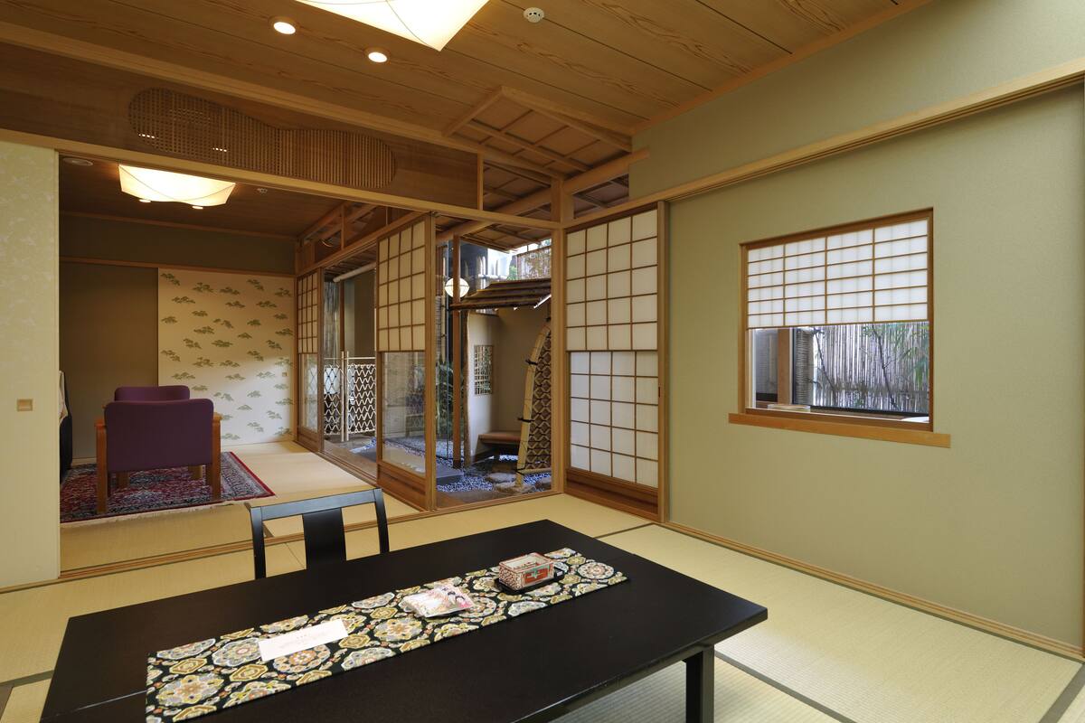 A traditional Japanese room with tatami flooring, a low table with a decorative table runner, and sliding doors with shoji screens.