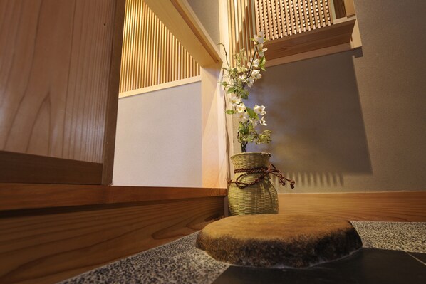 Un interior japonés tradicional con un banco de madera, una cesta de mimbre con flores y un suelo de esteras de tatami.