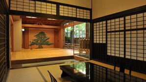 Una habitación japonesa tradicional con suelo de tatami, una mesa de madera baja y una puerta corredera de shoji.