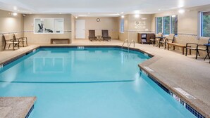 A swimming pool with lounge chairs and a sunbed area, surrounded by walls with a clock and a 'No Diving' sign. - Holiday Inn Express Hotel & Suites Tilton - Lakes Region by IHG (Tilton)