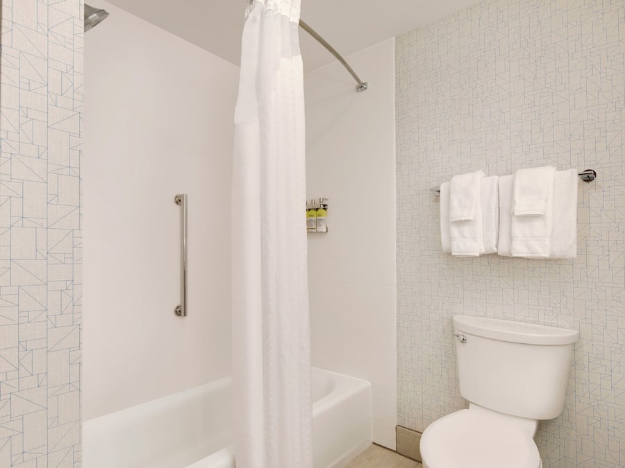 Un baño con ducha, bañera, inodoro y toallero.