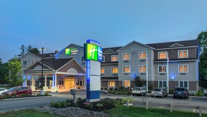 A Holiday Inn Express hotel with a modern design, multiple floors, and a parking lot with several cars. - Holiday Inn Express Hotel & Suites Tilton - Lakes Region by IHG (Tilton)