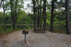 A picnic area with a grill and a bench near a lake surrounded by trees. - Holiday Inn Express Hotel & Suites Tilton - Lakes Region by IHG (Tilton)
