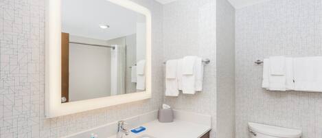 A modern bathroom with a large mirror, white sink, and toilet.