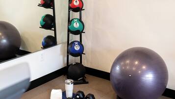 A gym with exercise balls, dumbbells, and a bench.
