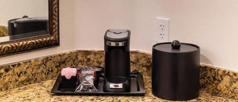 A kitchen counter with a coffee maker, a kettle, and a coffee pod holder.