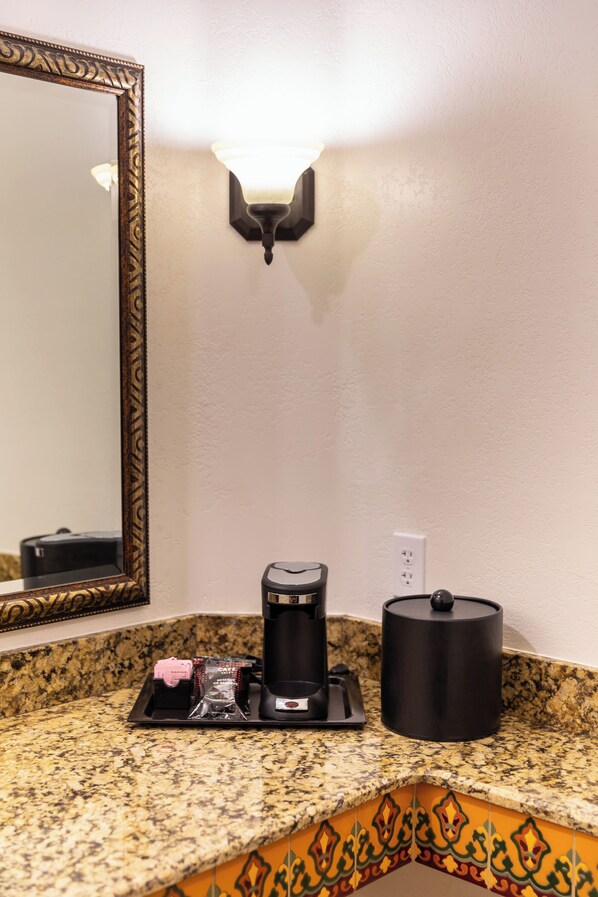 A kitchen counter with a coffee maker, a kettle, and a coffee pod holder.