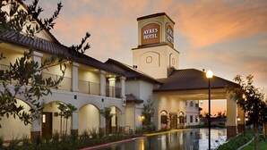 Un hotel con un patio central, entrada cubierta y un letrero que dice "AYRES HOTEL".