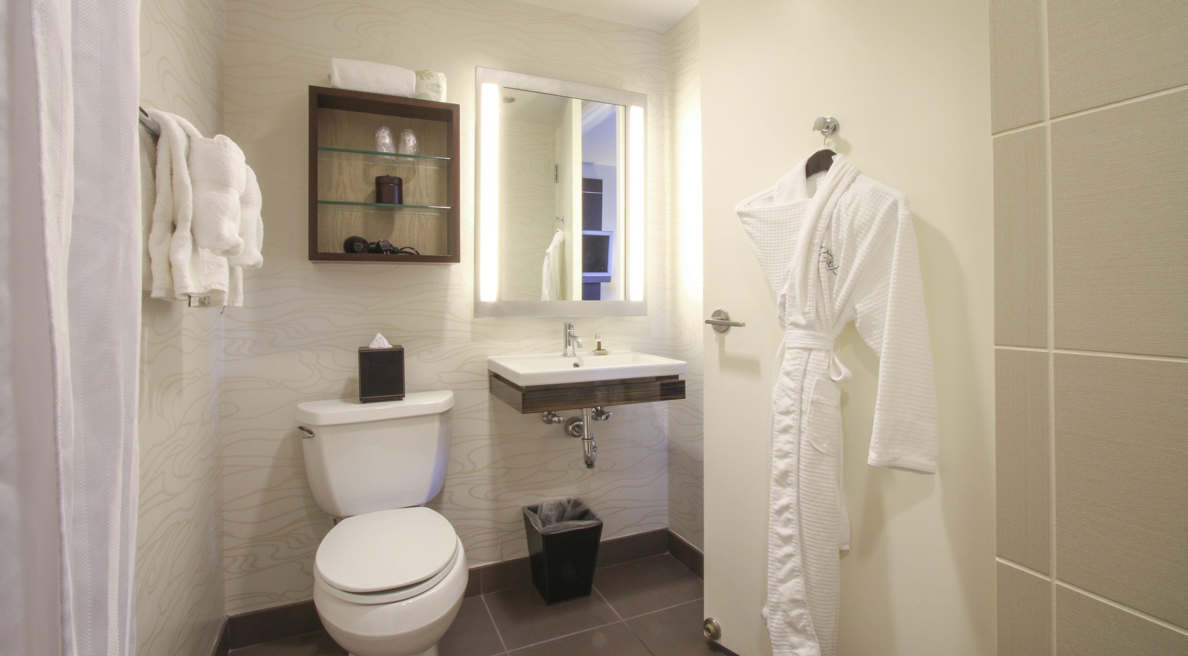 Un bagno con il water, un lavandino, uno specchio e un accappatoio appeso al muro.