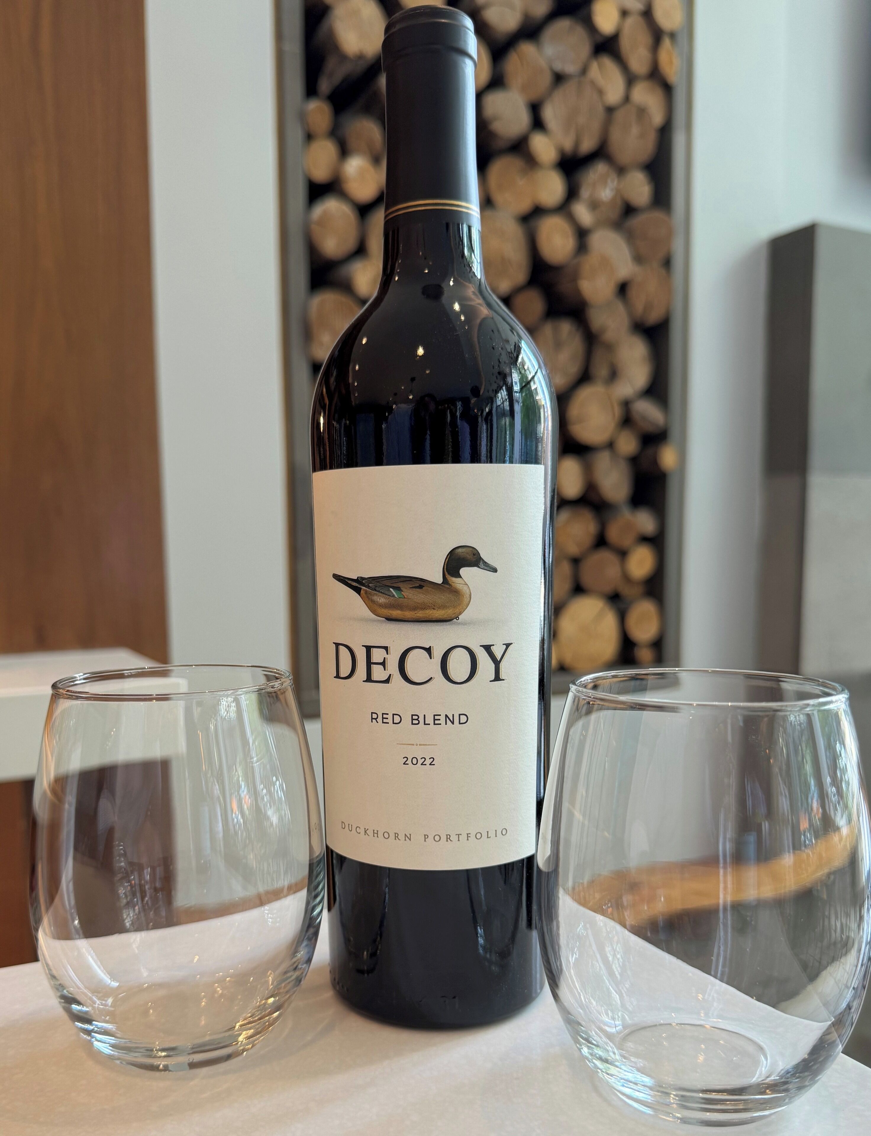 Una bottiglia di vino blend rosso Decoy del 2022 con due bicchieri vuoti accanto.