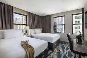 A hotel room with two beds, a dining table with chairs, a city view, and a minibar. - Hotel Felix River North/Magnificent Mile (Chicago)