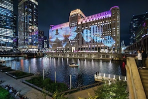 A large building with illuminated windows and a river in front. - Hotel Felix River North/Magnificent Mile (Chicago)
