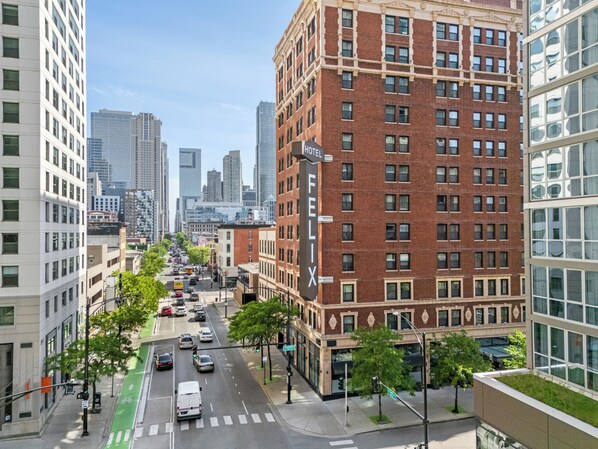 Un hotel de varios pisos con un llamativo letrero 'FELIX', rodeado de edificios modernos y una calle concurrida con coches y un carril bici verde.