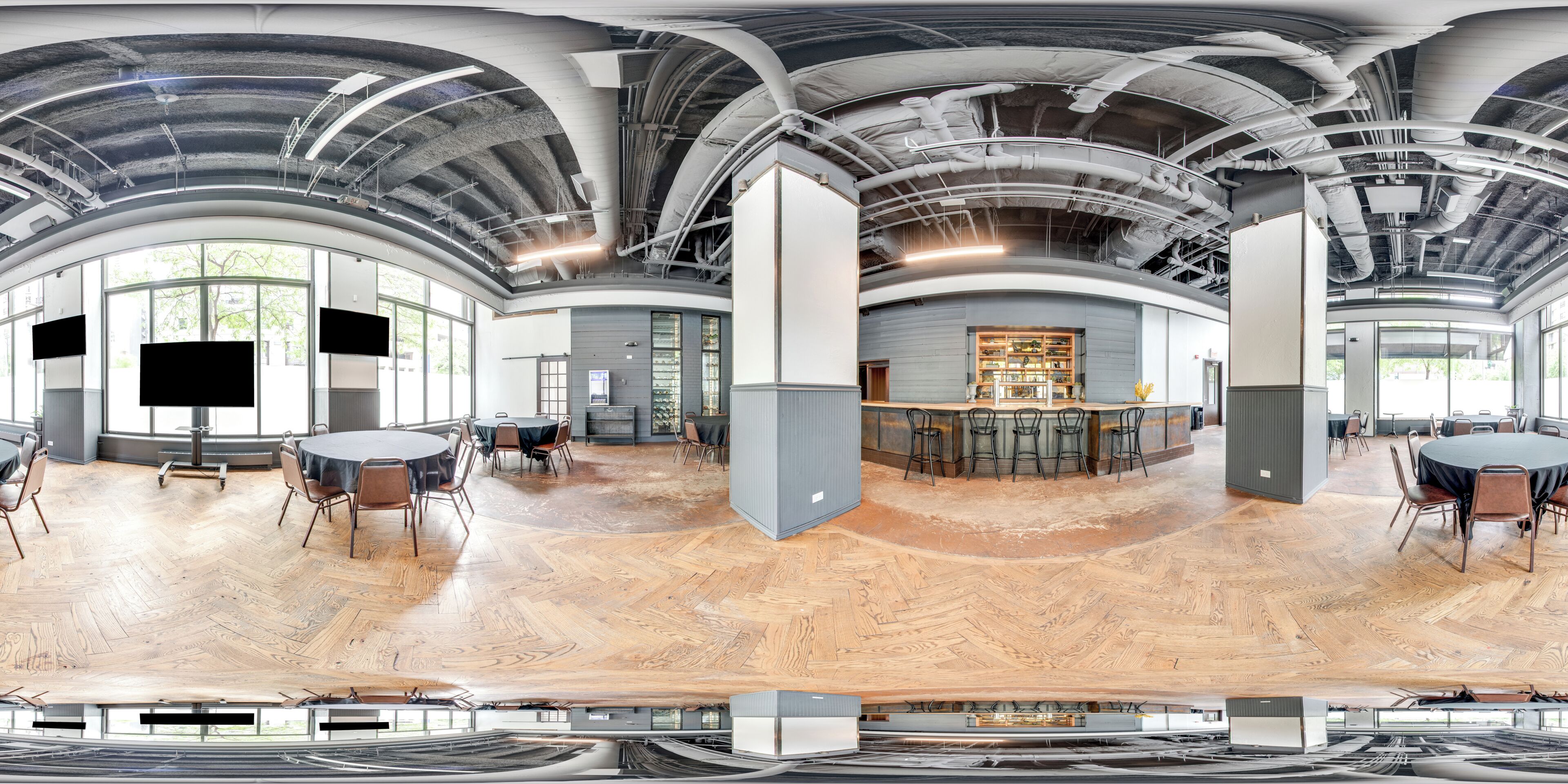 A panoramic view of a modern interior space with curved ceilings, large windows, and a central bar area.