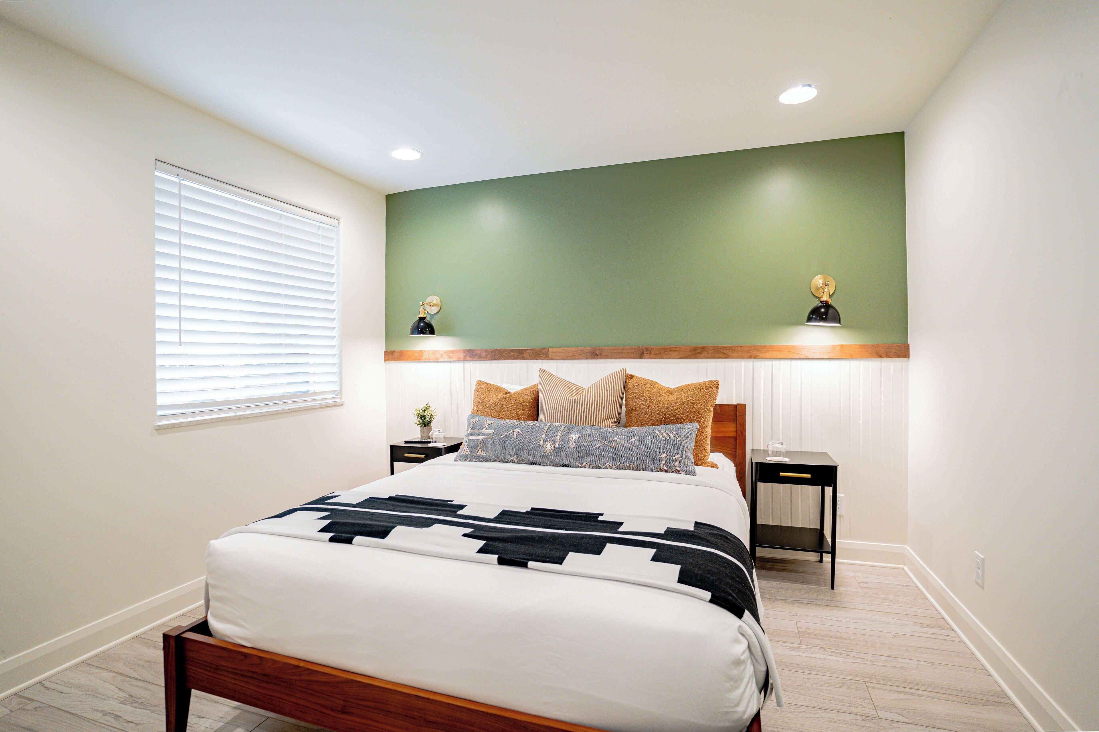 A bedroom with a bed, bedside tables, and a green accent wall.