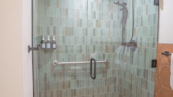 A glass-enclosed shower with a tiled floor and a glass door.