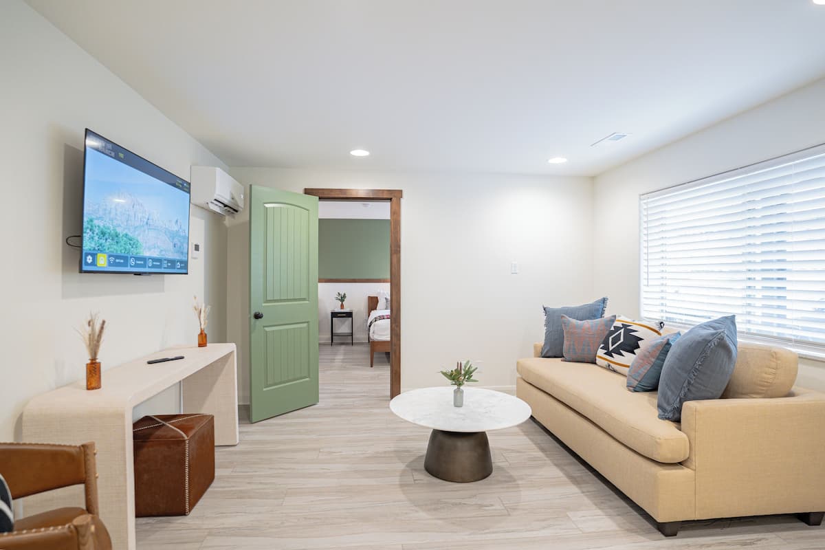 A modern living room with a sofa, a coffee table, and a TV mounted on the wall.