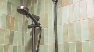 Une douche équipée d’un pommeau de douche à main et d’un flexible également à main.
