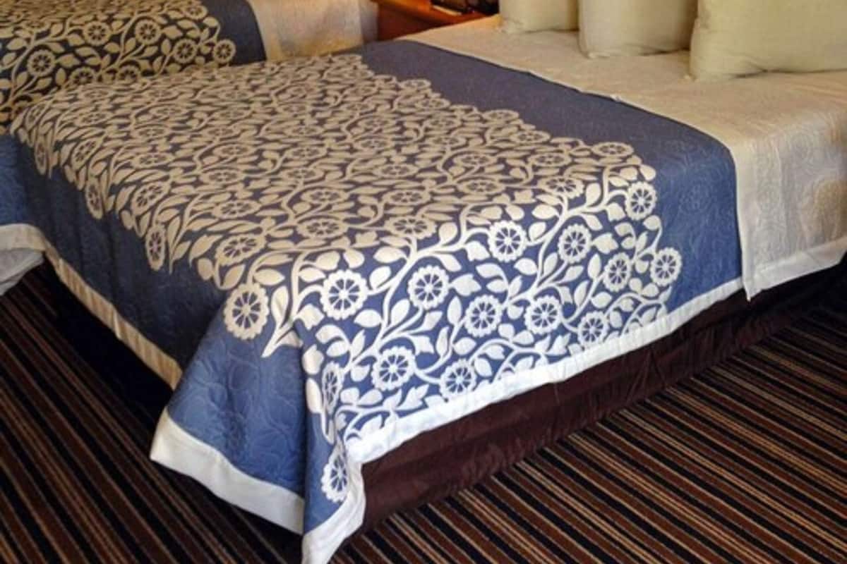 Une chambre d’hôtel avec deux lits, une table de chevet avec une lampe et une couvre-lit à motifs.