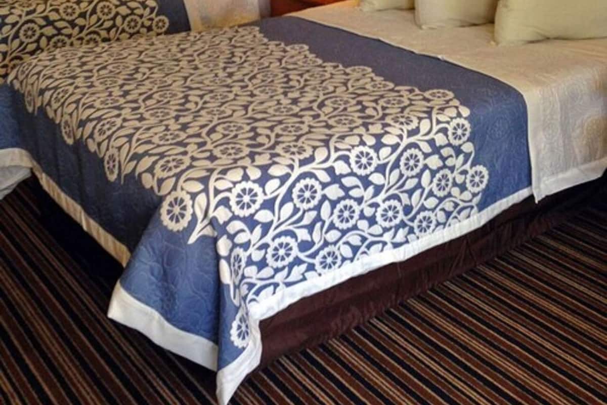 Une chambre d’hôtel avec deux lits, une table de chevet avec une lampe et une couvre-lit à motifs.