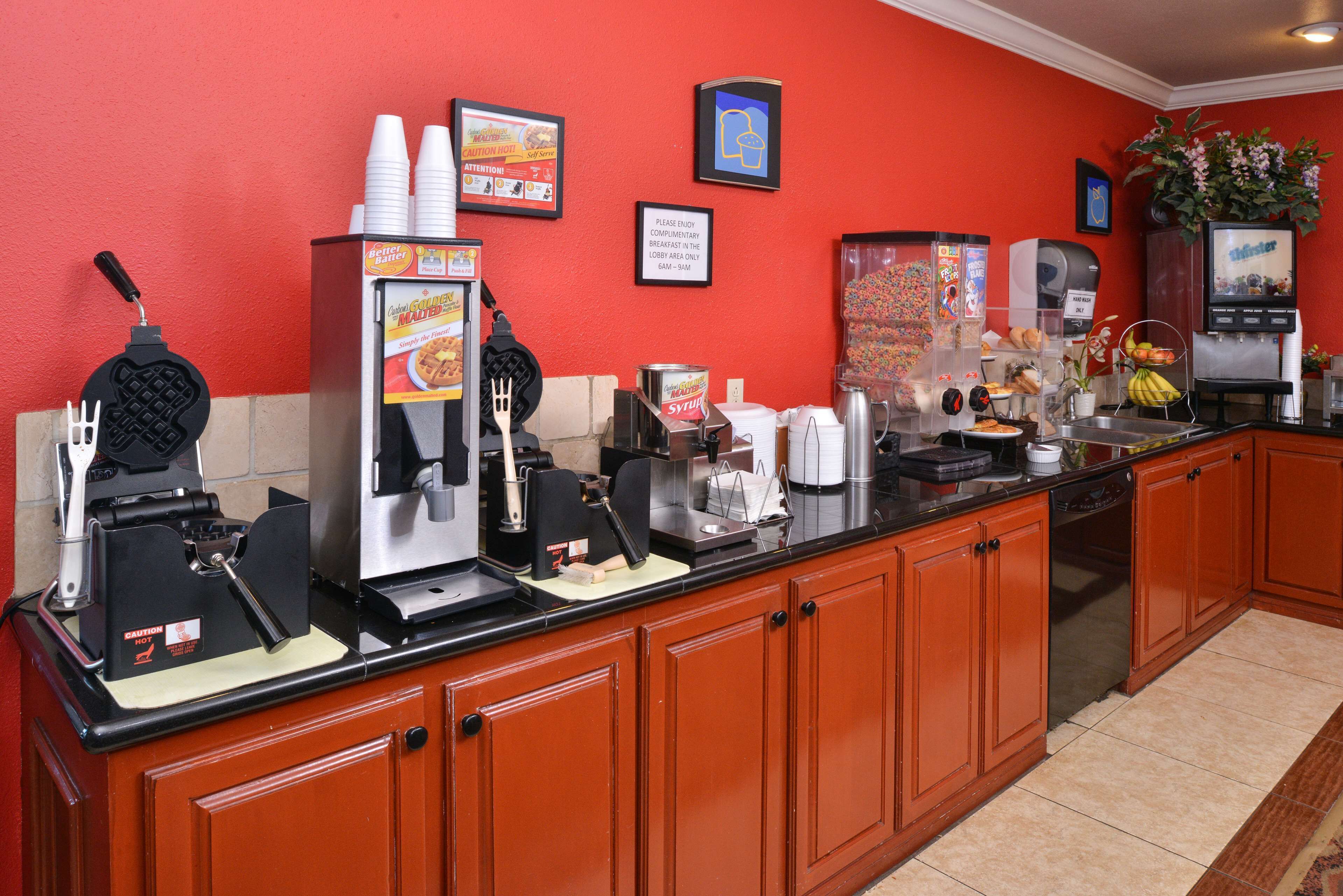 Un buffet pour le petit-déjeuner avec des appareils à gaufres, des machines à café et un distributeur de boissons.