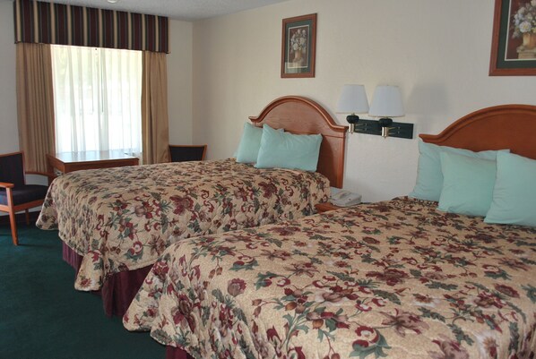A hotel room with two beds, a desk, and a chair.