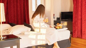 A hotel room with a bed, a bedside table with a lamp, a television, and a breakfast tray on the bed.
