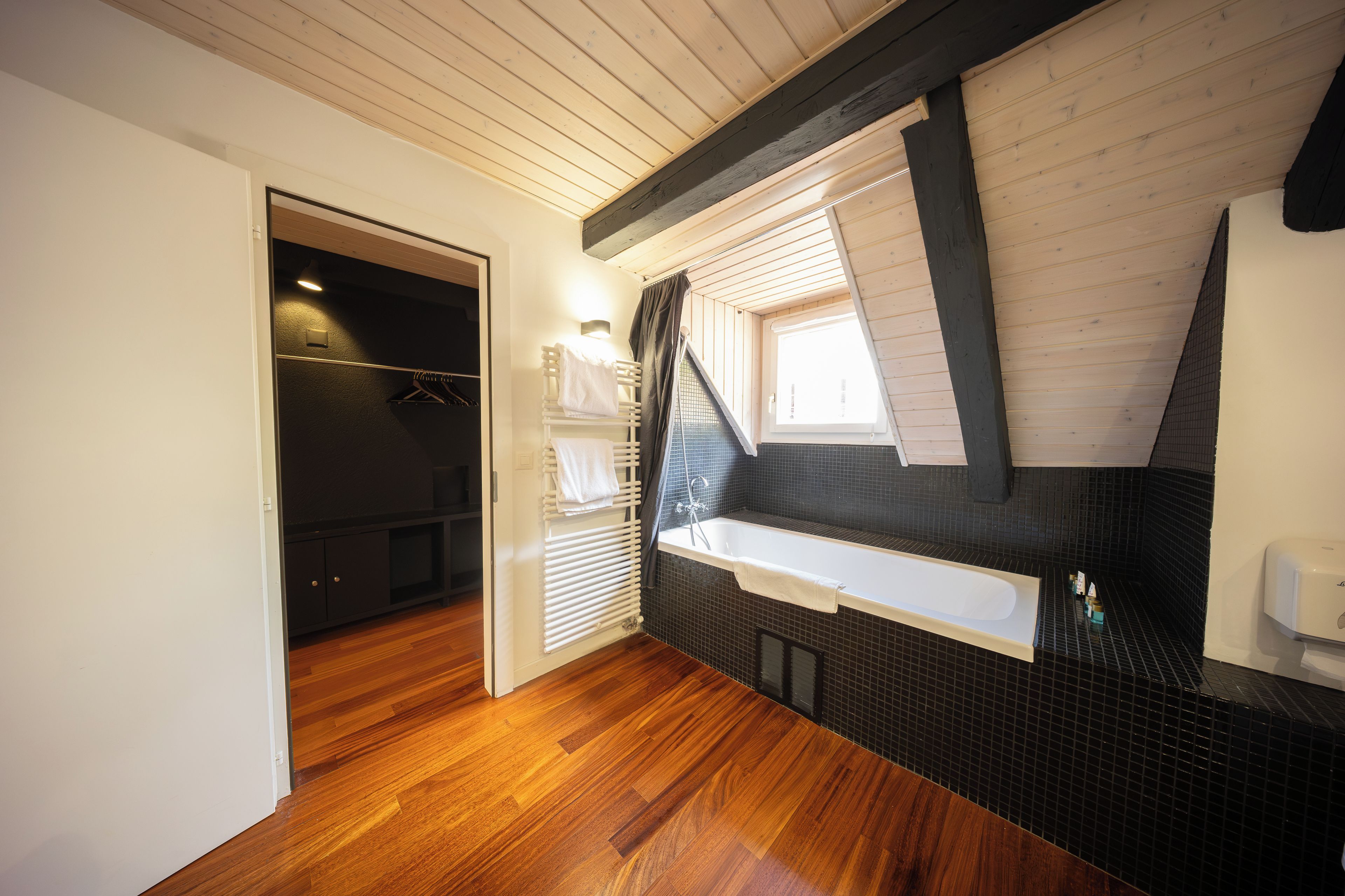 Une salle de bain moderne avec un plancher en bois, une baignoire, une fenêtre avec vue et un porte-serviettes.