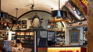 A bar with a wooden counter, shelves with bottles, and a chalkboard menu.